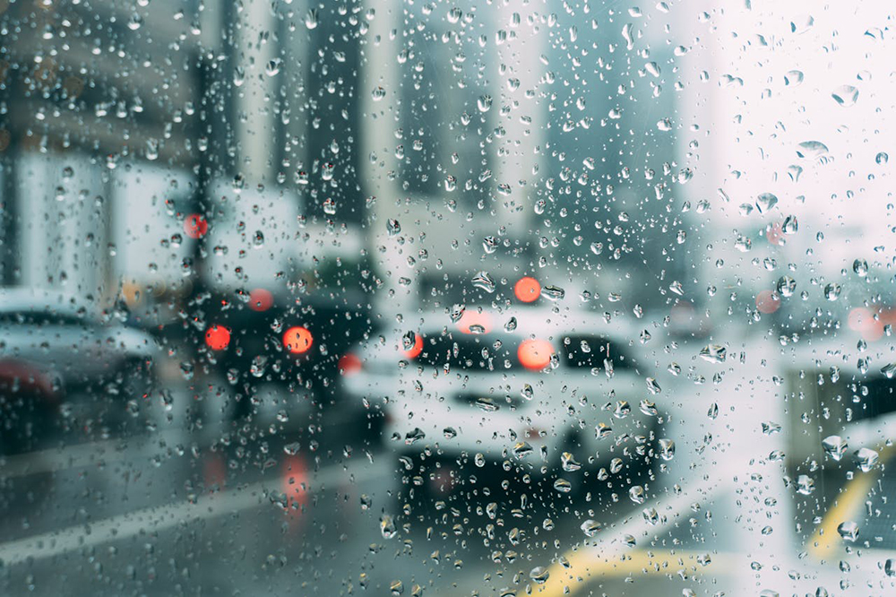 Raindrops on a glass and cars on the street that can be seen through glass