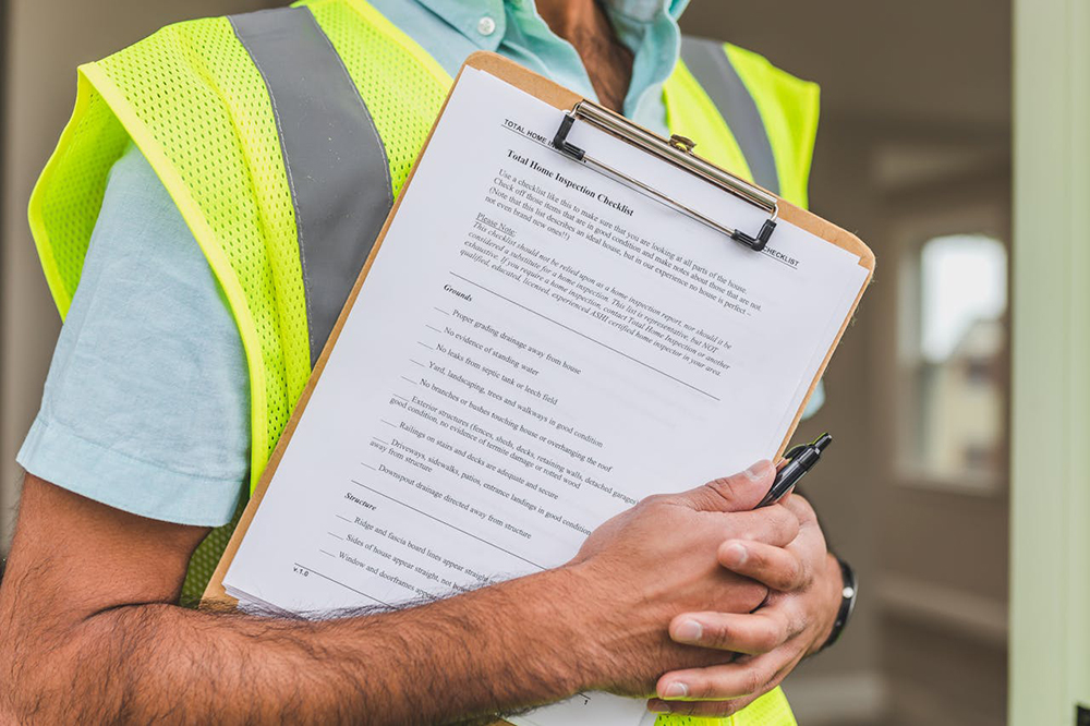 Person in a safety vest holding a checklist of a home inspection