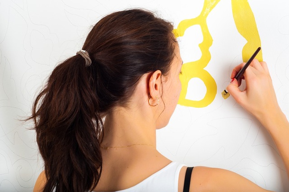 A woman painting on a wall, one of kid-friendly renovation ideas