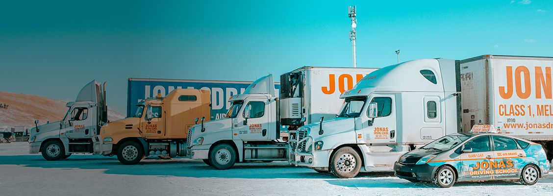 Jonas Driving School sign on trucks and trailers in a parking lot