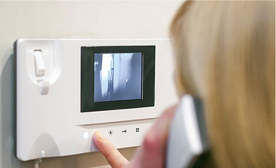 A woman using a Video Intercom System installed by Integral Konnect to make a call for communication process