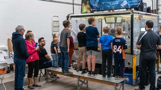 A professional photograph taken by Darkstrand Visuals depicts a group of kids viewing large electronic devices.