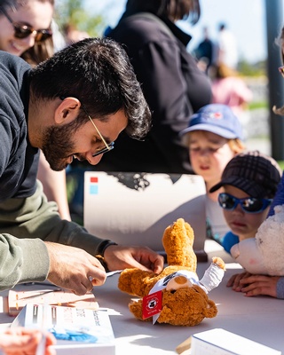 A person showing how to repair a damaged teddy bear to a kid picture taken by Darkstrand Visuals