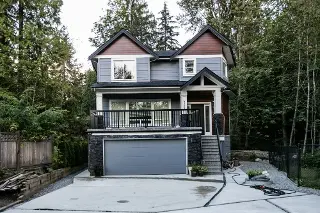 Robson Custom Home beckons with its stunning design, set against the backdrop of a lush forest