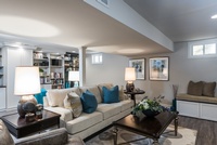 Sofa with blue cushions between the lamps by R Designs, LLC