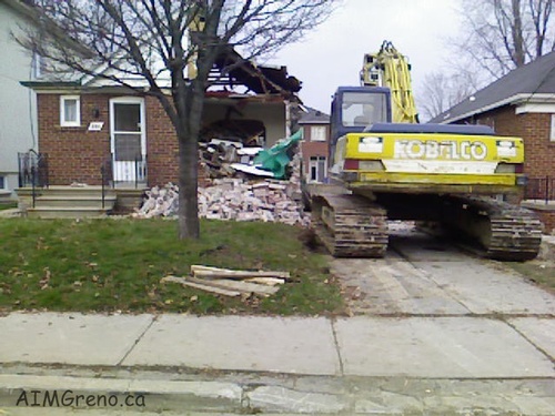 Excavator Demolishing a House
