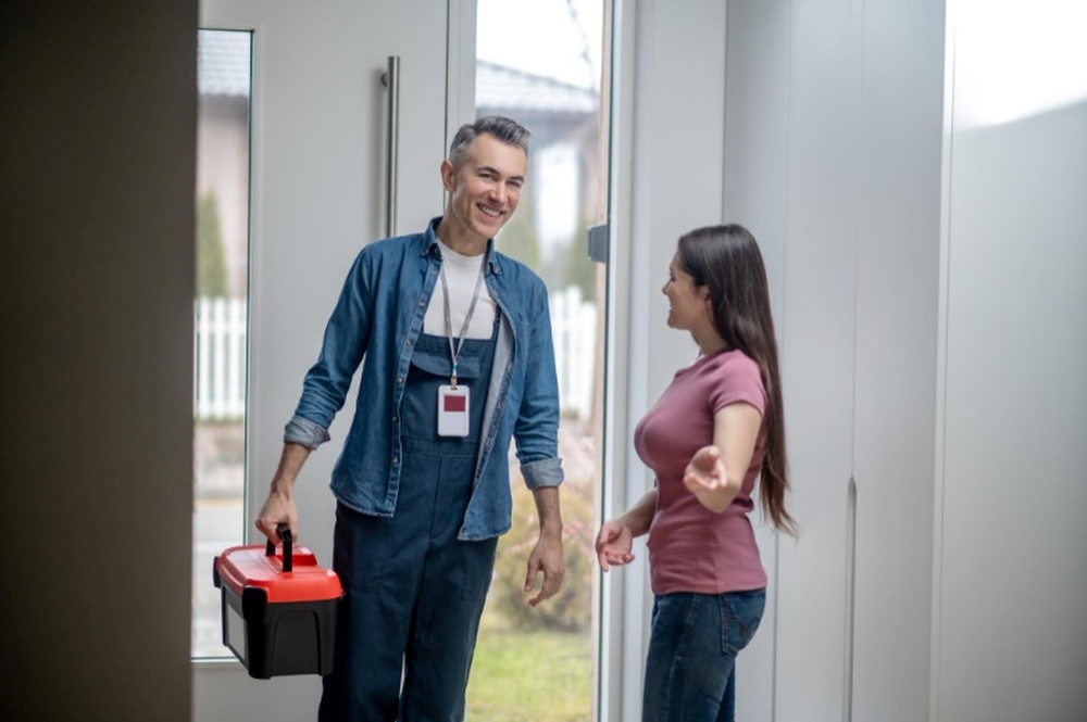 A woman inviting a man in blue clothes into her house since she knows that inspections benefit home sellers