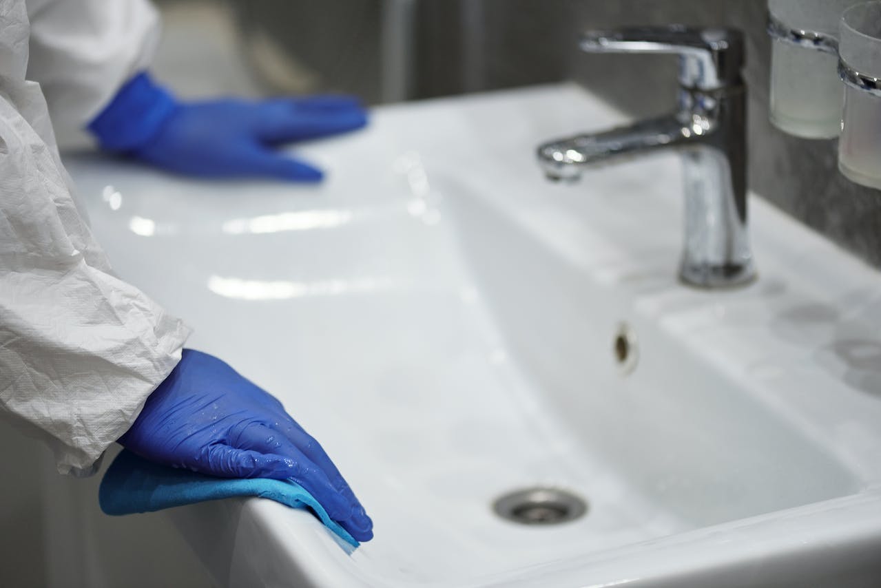A person with gloves at a bathroom sink