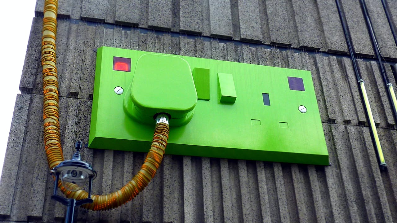 Green rectangular corded machine on a gray wall 