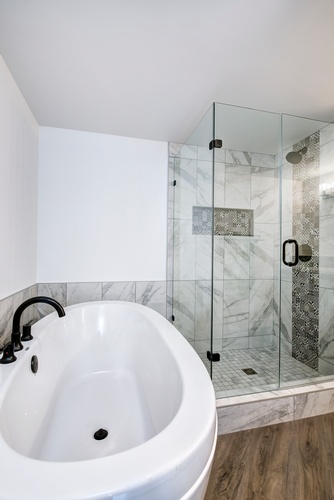 IN THIS BATHROOM, THE BEAUTIFUL MARBLE TILE FROM THE SHOWER, CONTINUES ALONG THE WALL AND SURROUNDS THE NEW TUB TO KEEP WALL CONSISTENCY.