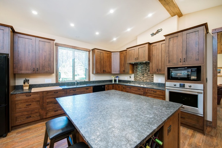 WHEN THE INTENTION IS TO ENTERTAIN, HAVE A BIG ISLAND WITH PLENTY OF ROOM TO GATHER AROUND. THIS KITCHEN WITH NATURAL WOOD CABINETS, HAS PLENTY OF COUNTERTOP AREA INCLUDING A WOOD CUTTING BOARD INSERT.