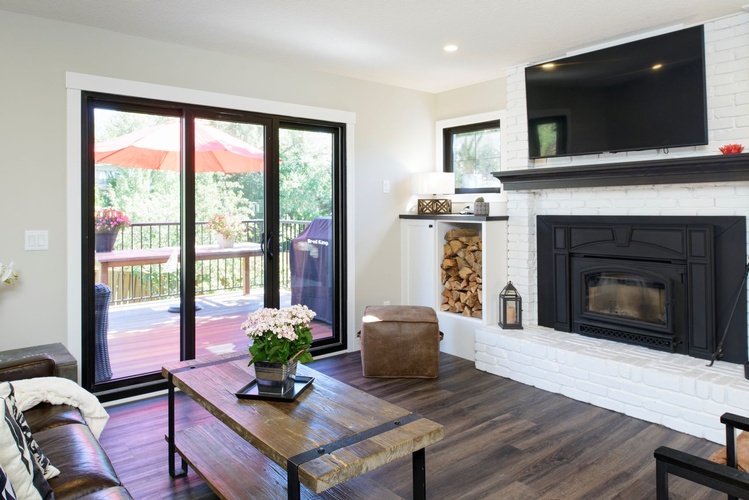 HERE, THE SAME FIREPLACE WAS KEPT, THE SURROUNDING BRICKS WERE PAINTED WHITE TO MODERNIZE THE LIVING ROOM AND A BLACK MANTLE WAS INCLUDED FOR A BETTER COMBINATION WITH THE NEW BLACK SLIDING DOOR AND WINDOW.