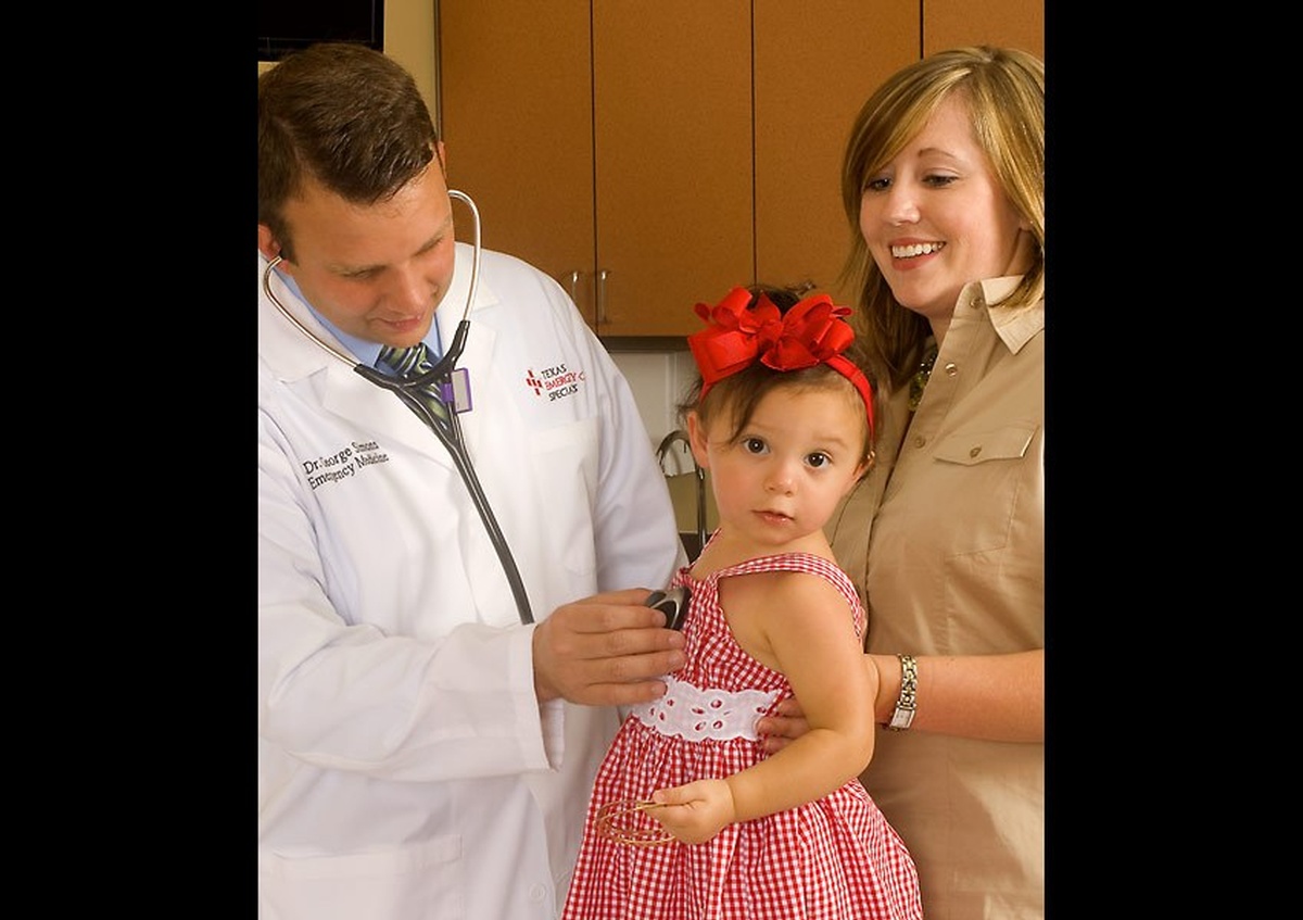 A doctor examining a child while her mother looks on -  Professional Photography in Texas by Joe Robbins