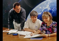 3 people discussing work on sheets - Joe Robbins Photography