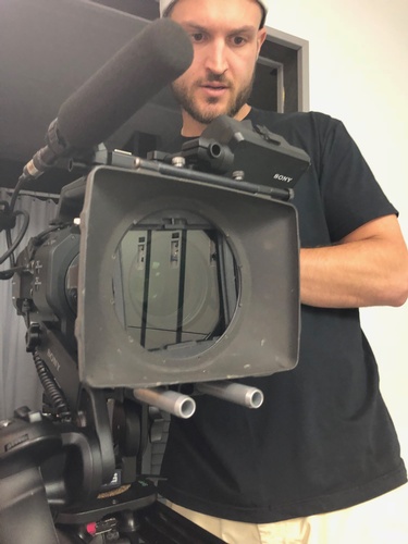 Videographer at Merlin Productions LLC handling a video camera with care