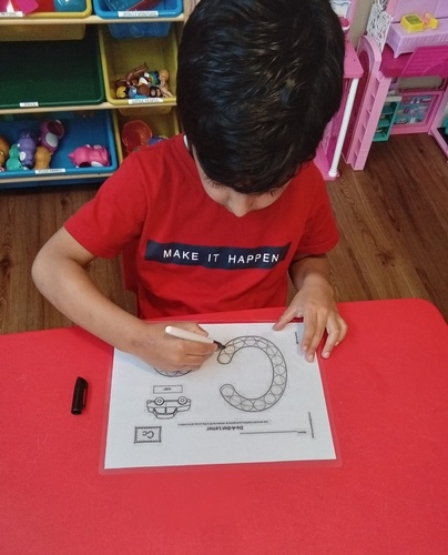 Child tracing the alphabet C on paper at HIDE ‘n' SEEK DAYCARE - Day Care Center in Brampton, Ontario