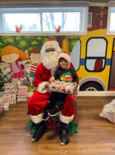 Santa giving Theo gifts for christmas at HIDE ‘n' SEEK DAYCARE - Licensed Childcare Center in Brampton, Ontario