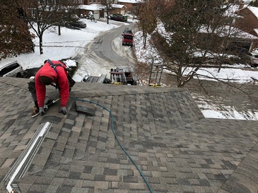 Expert roofer installing shingles for the home roof in the snowy region by Imperial Roofs and Aluminum