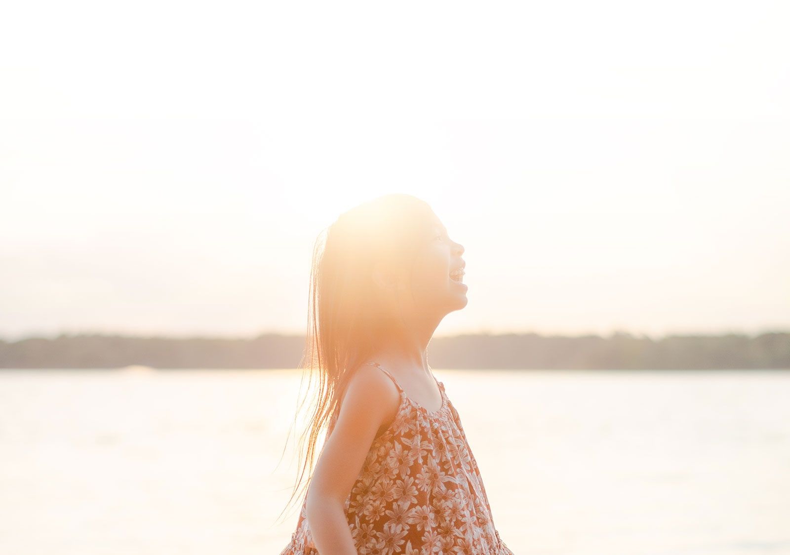 Spontaneous moment of a girl smiling out in front of a body of water captured by Flores Photography in Toronto