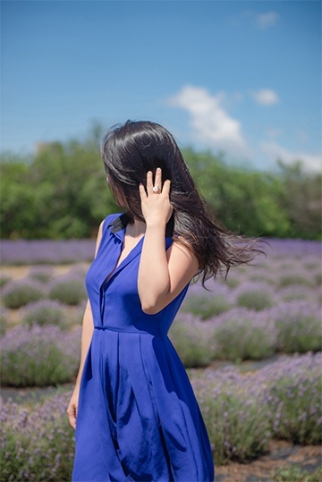 Headshot of a woman in a blue dress standing in a lavender field captured by Flores Photography in Toronto