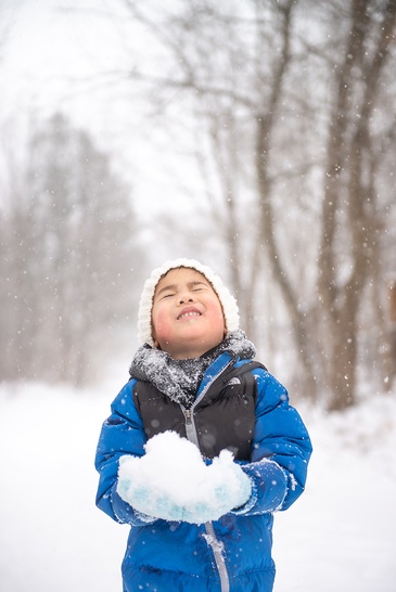 Portrait of a young child enjoying in snow captured by Flores Photography in Toronto