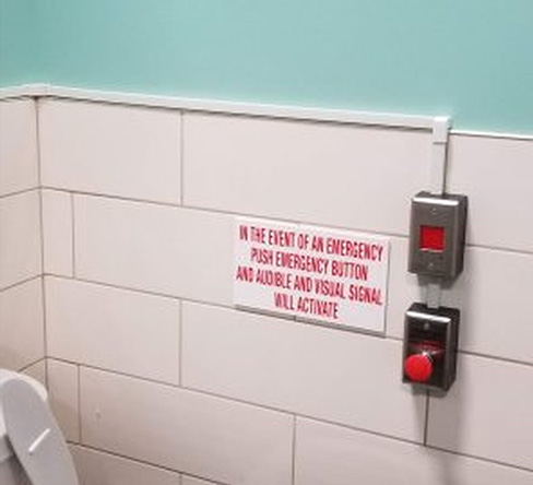 Toilet with emergency button sign for urgent assistance installed by Integral Konnect.