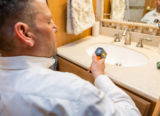 Home Inspector inspecting a wash basin with a thermal device during a home inspection
