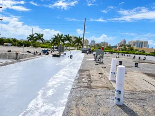 Commercial flat roof with white roofing surface and material rolls