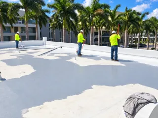 Roof-coating crew in neon shirts and white hardhats