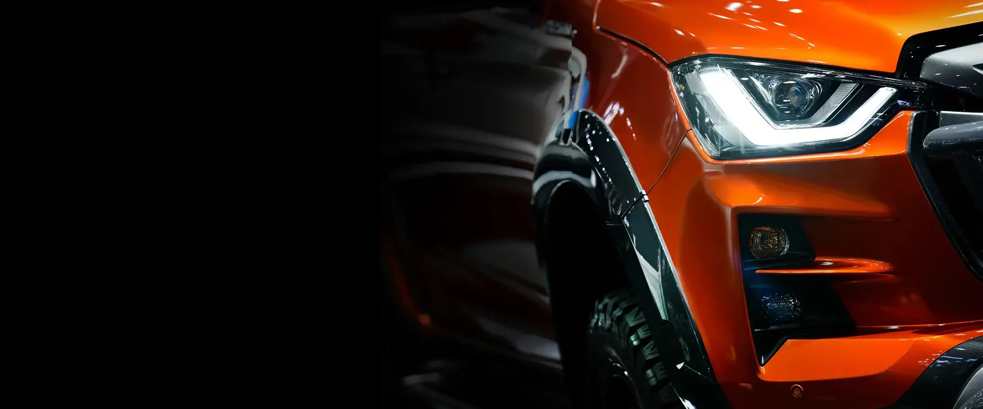 Close-up of an orange colored vehicle headlight and front bumper at an Auto Body Shop in Merriam