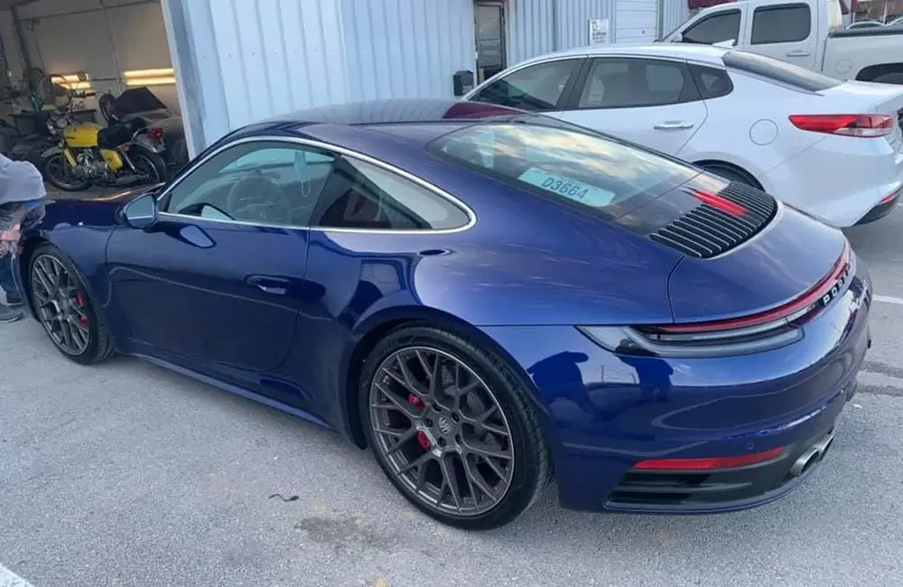 Blue Porsche parked outside an Auto Body Shop in Merriam after exterior repair and refinishing.