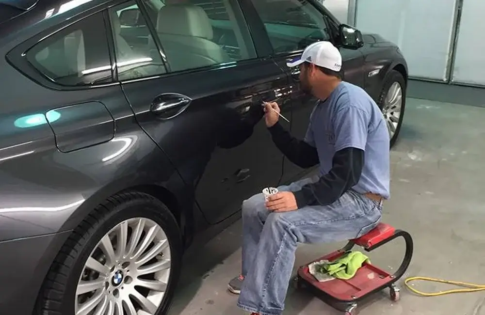 Auto Body Technician performing paint touch-up on a BMW at an Auto Body Shop in Merriam.